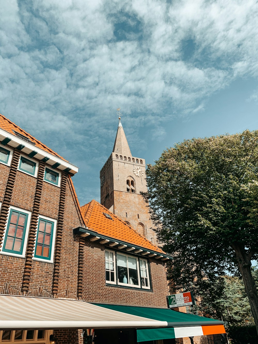 Braunes Betongebäude in der Nähe von grünen Bäumen unter blauem Himmel tagsüber