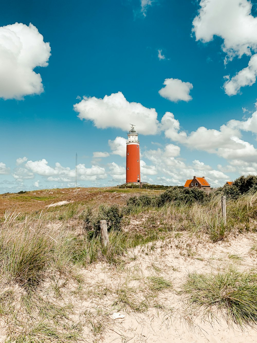 Phare orange et blanc sous le ciel bleu pendant la journée