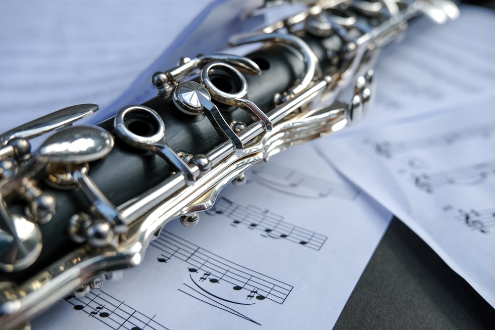 black and silver flute on white musical sheet