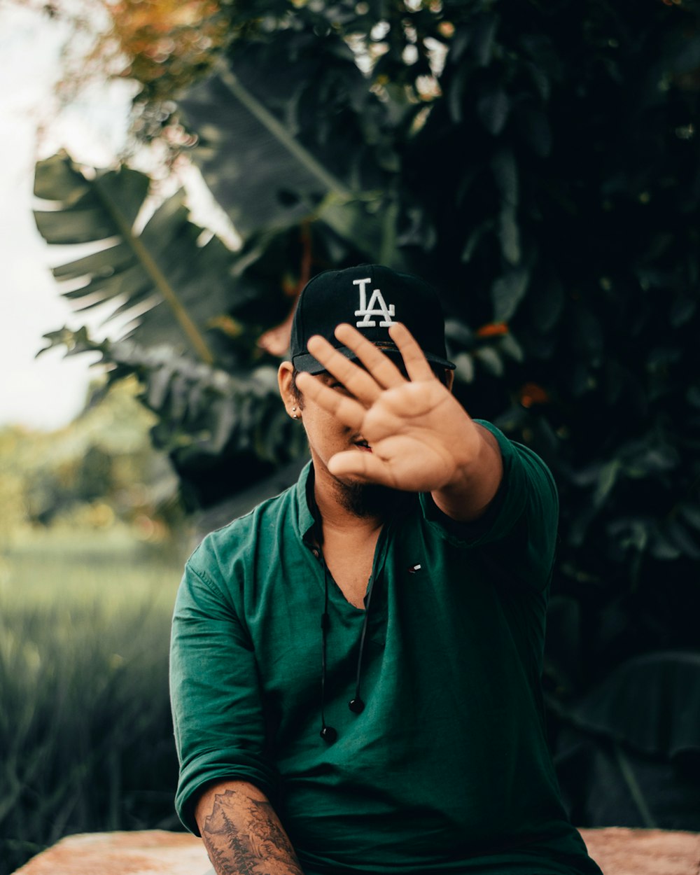 uomo in camicia verde a maniche lunghe che si copre il viso con la mano