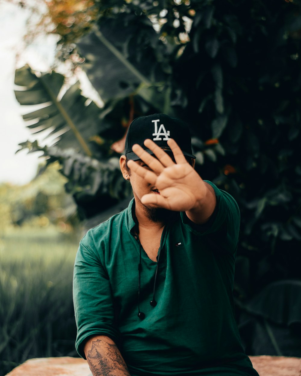 man in green long sleeve shirt covering his face with his hand