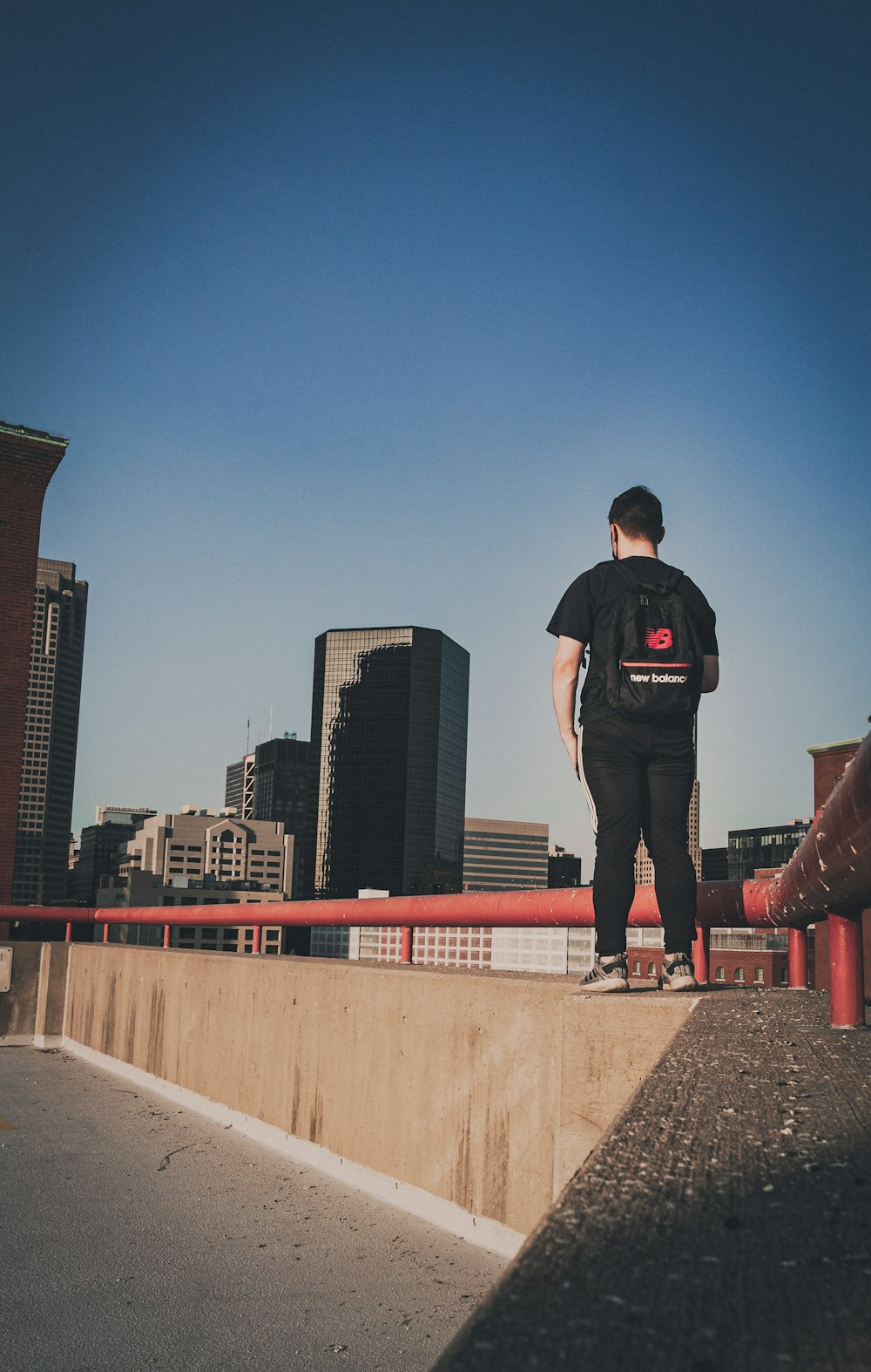 man in black t-shirt and black pants standing on concrete wall during daytime