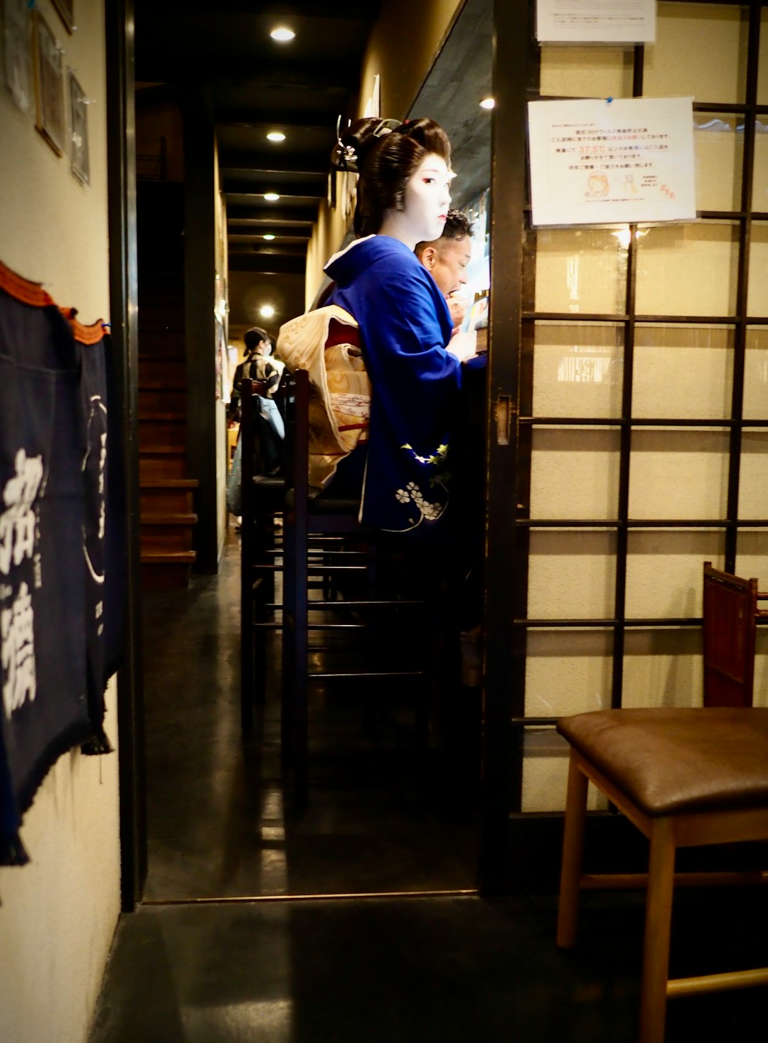 man in blue dress shirt and black pants standing beside brown wooden door