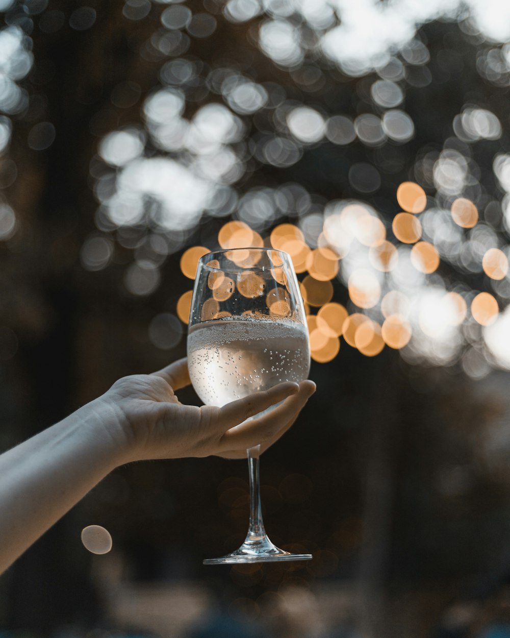 person holding clear drinking glass with brown liquid