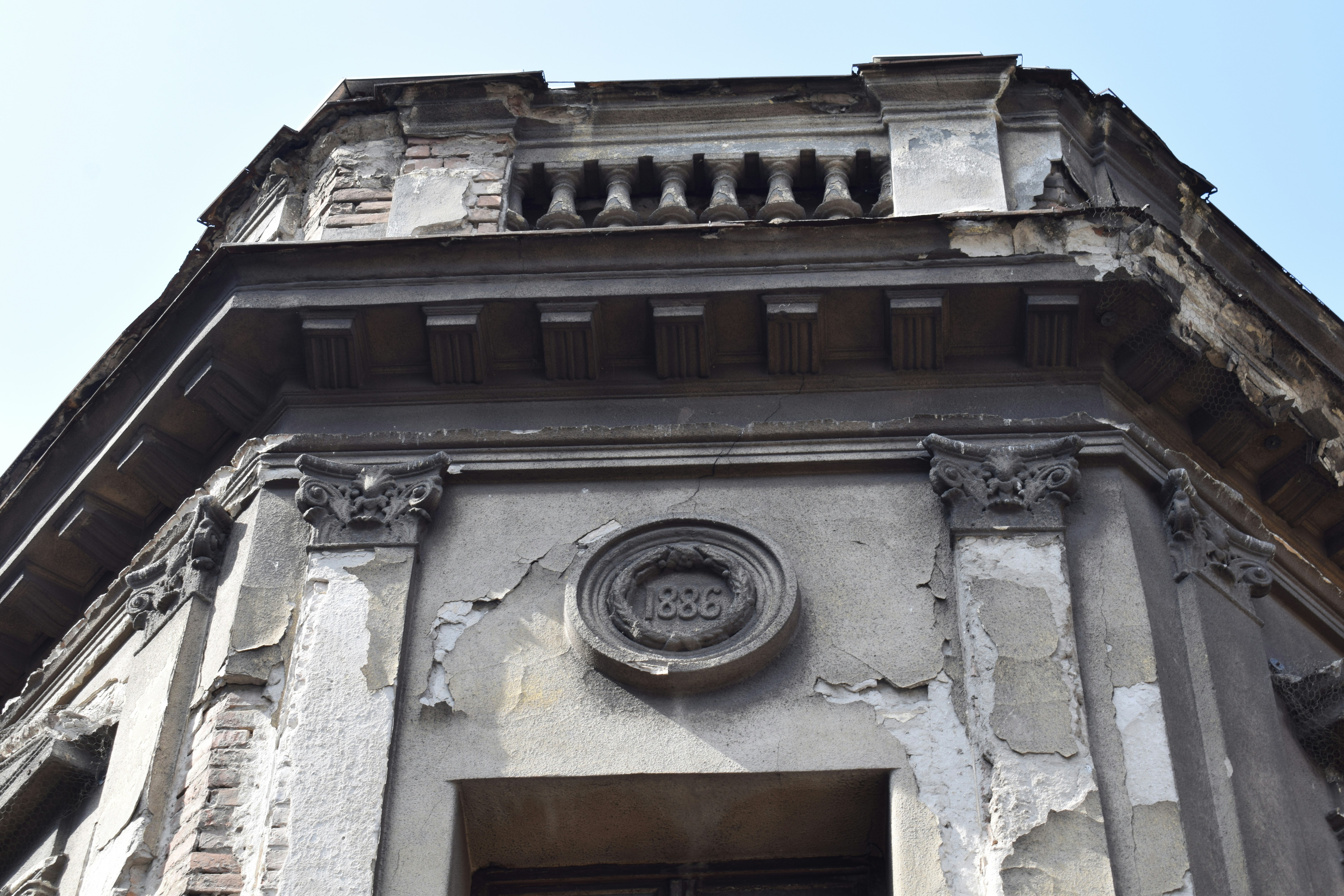 A close-up of a historic building facade showing detailed masonry and signs of wear.
