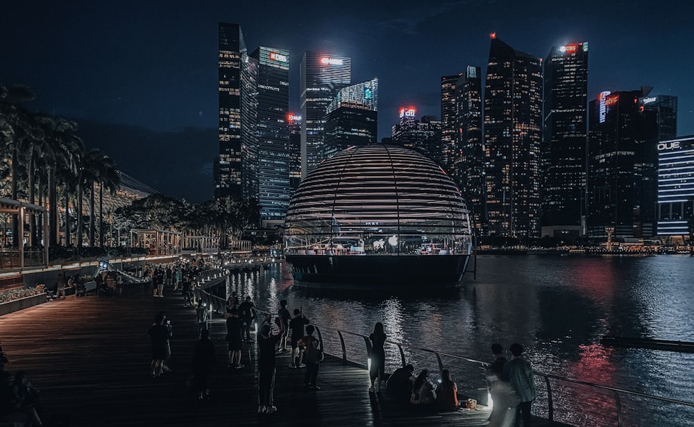 people on boat on water near city buildings during night time