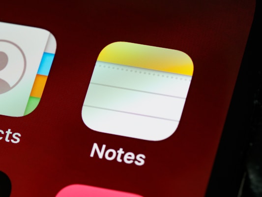 Close-up view of a smartphone screen displaying app icons, specifically the 'Notes' app with a notepad-like design and part of the 'Contacts' app icon visible.