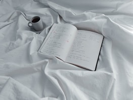 An open notebook with handwritten notes and a cup of coffee on a wooden table.