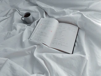 An open journal showing neat handwritten notes beside a cup of coffee.
