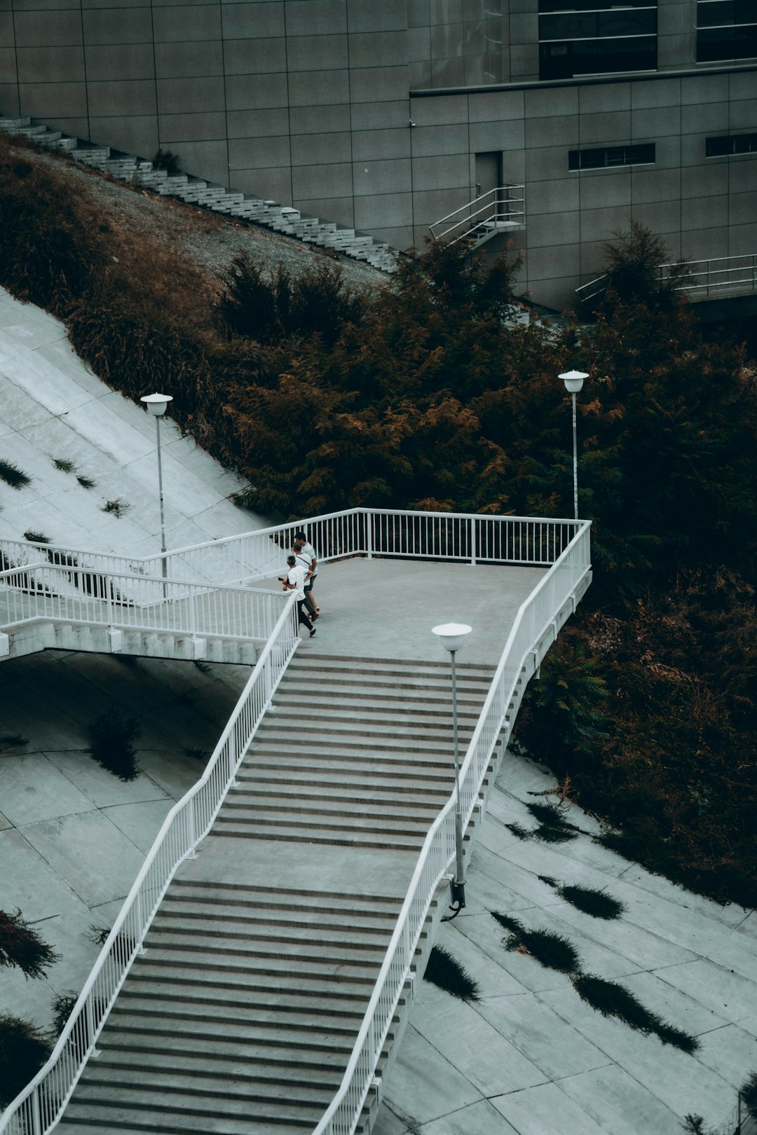 man in white shirt walking on white concrete bridge during daytime