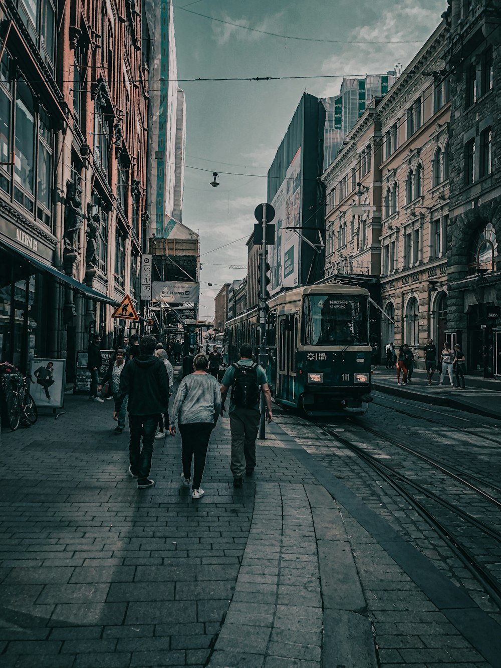 people walking on sidewalk near green tram during daytime