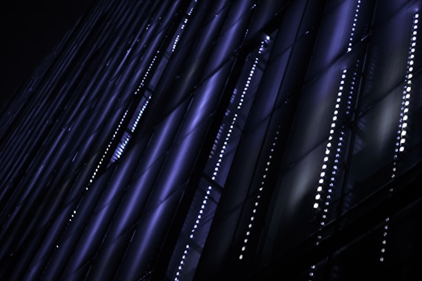 A sleek digital grid glowing with cobalt blue and vibrant orange waves flowing over a dark charcoal background.