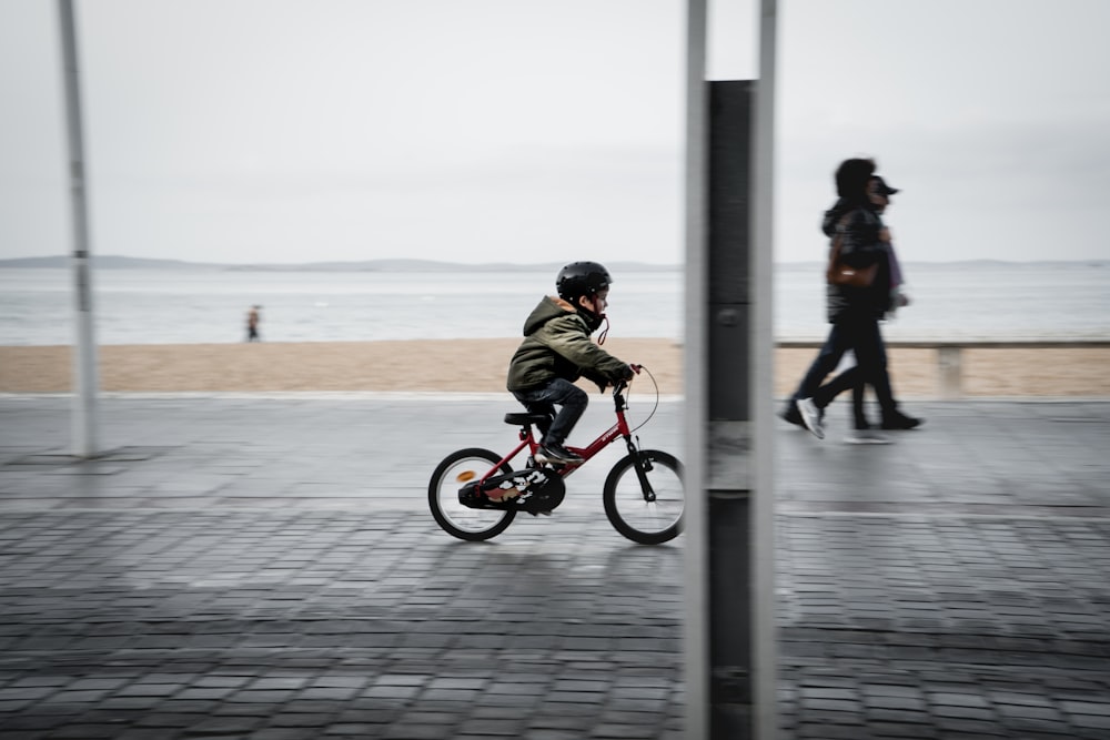 Hombre en chaqueta negra montando en bicicleta roja durante el día