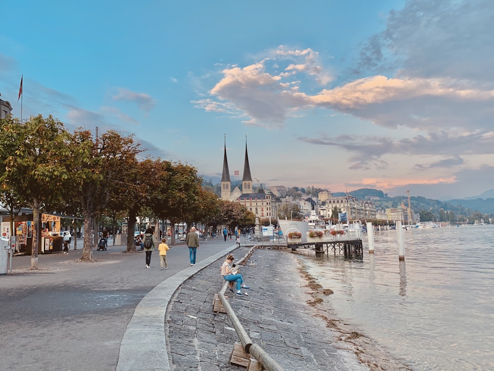 people walking on sidewalk near body of water during daytime