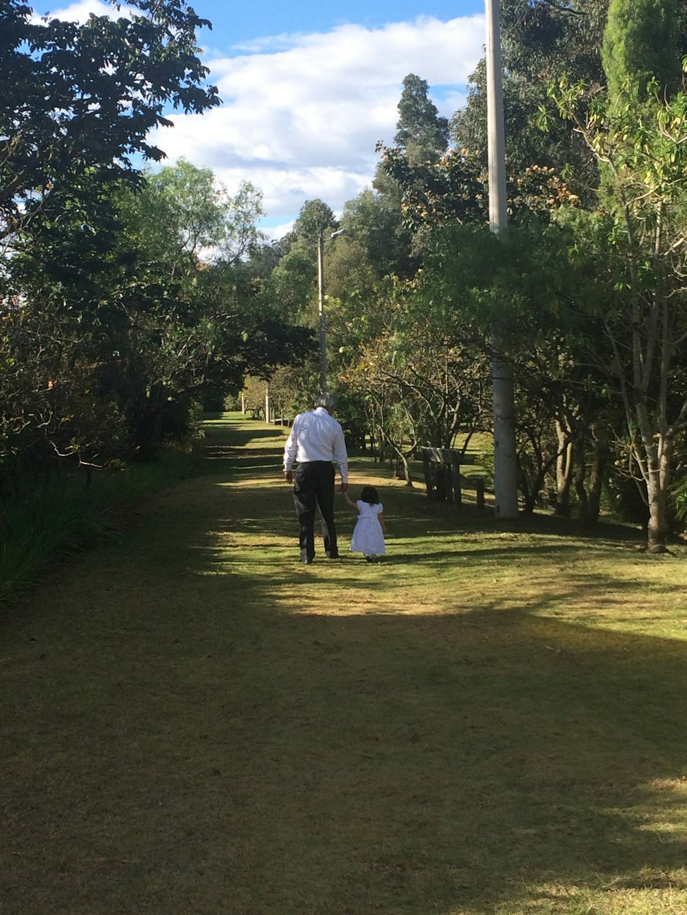 man in white dress shirt walking on green grass field during daytime