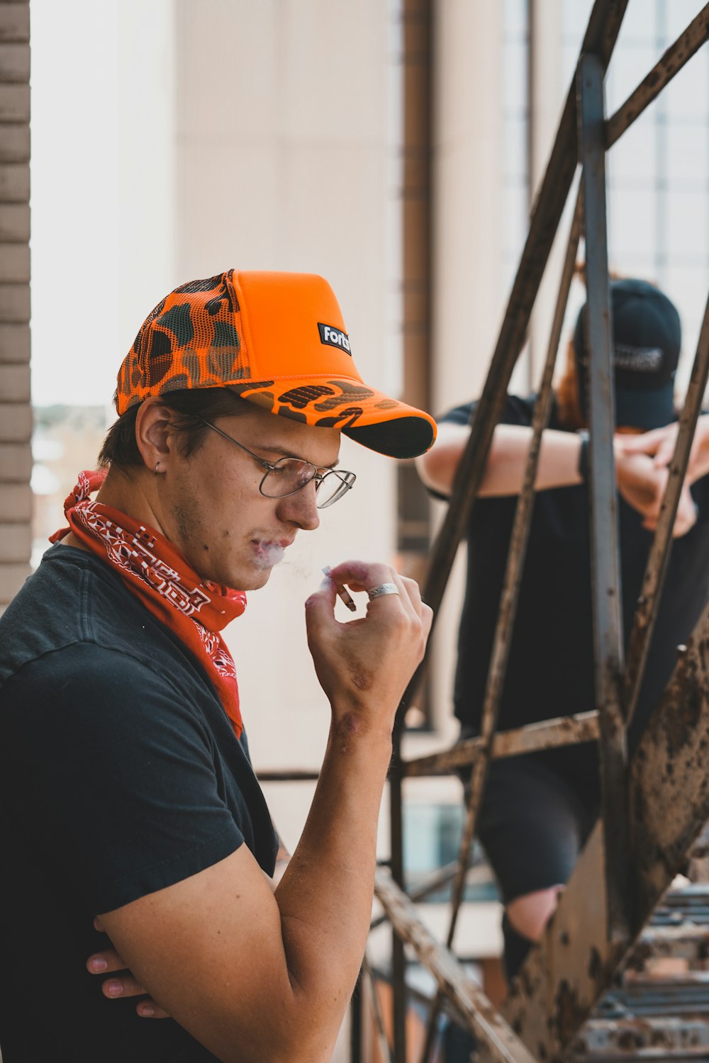 man in black shirt wearing orange cap and red and white scarf