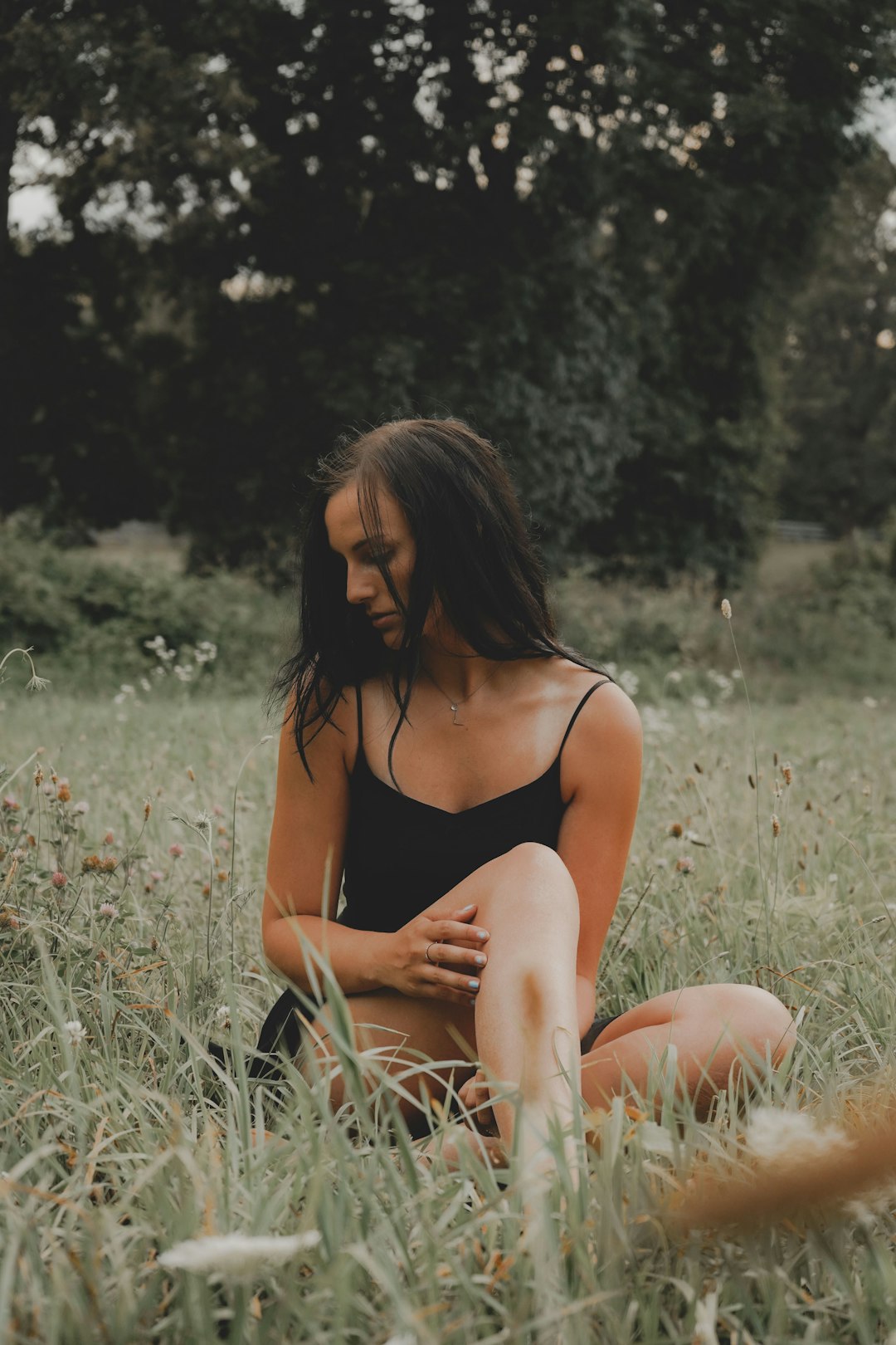 woman in black bikini sitting on grass field during daytime