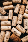 A collection of wine corks scattered across a surface, each stamped with the logo and name 'Casa Fontanari'. The corks vary in size, color, and texture, indicating they may have been used for different bottles of wine. The arrangement is casual, giving a sense of abundance and variety.