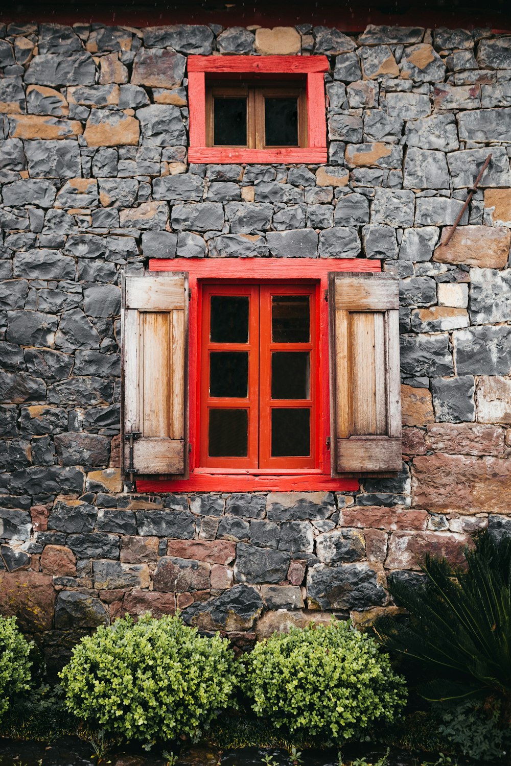 ventana de madera roja sobre pared de ladrillo gris