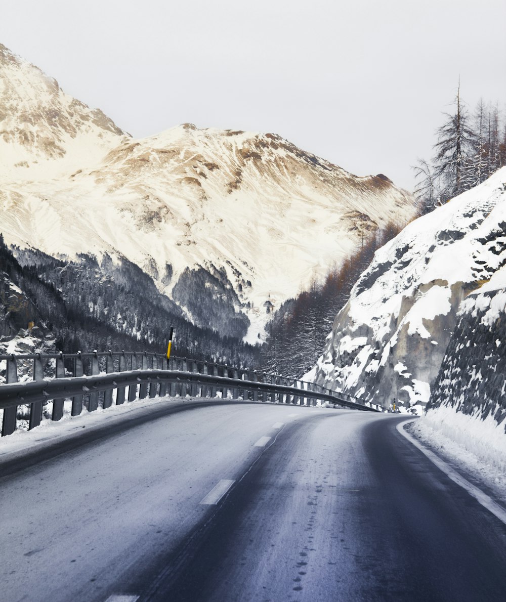 Schwarzes Auto tagsüber auf der Straße in der Nähe des schneebedeckten Berges