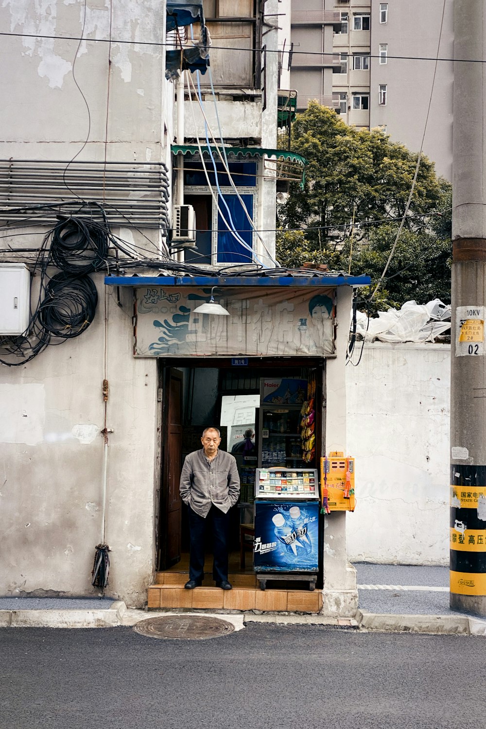 woman in gray jacket standing in front of blue and white store during daytime