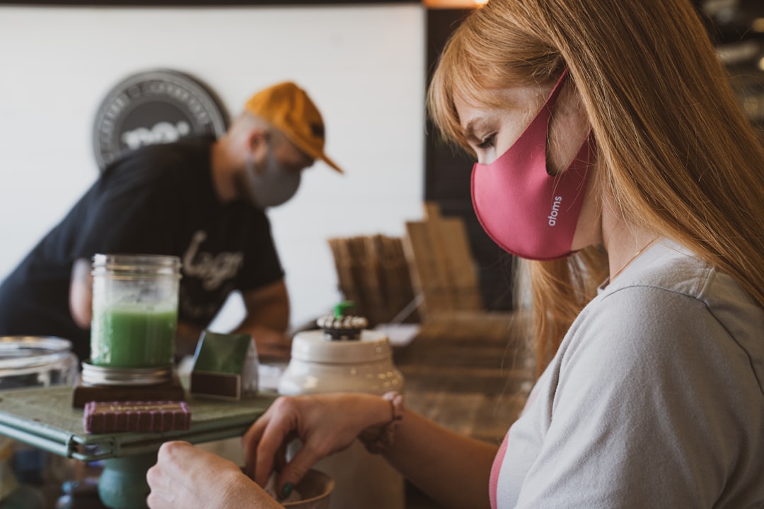 Two workers wearing face coverings preparing a smoothie to serve to their customers.