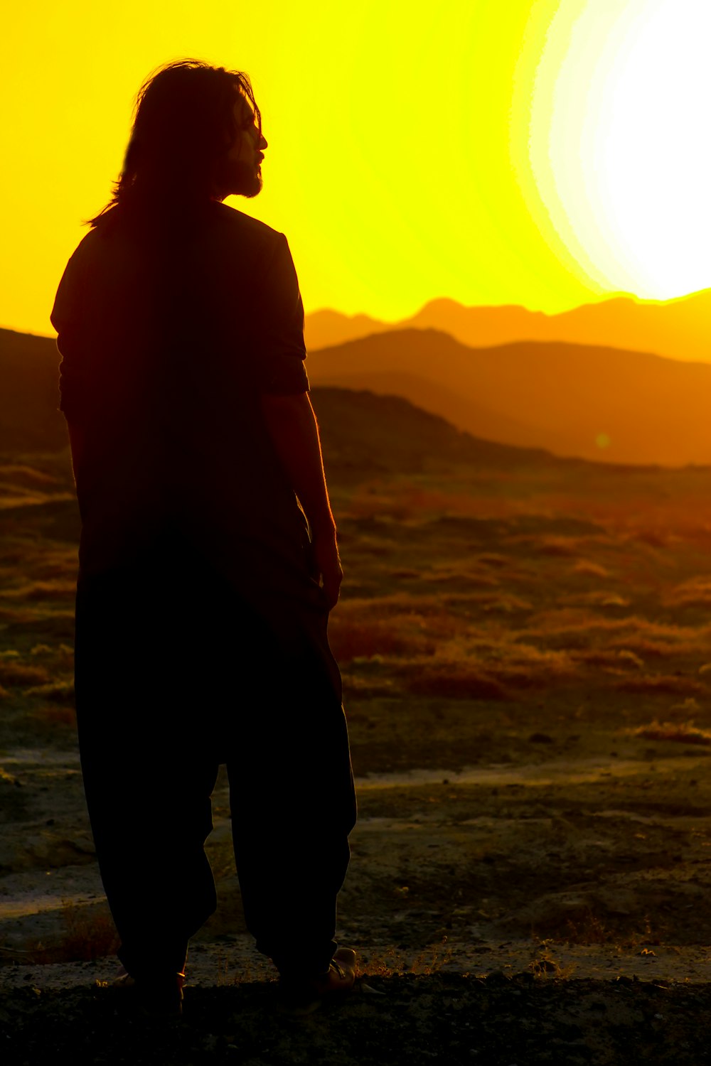 silhouette of man standing on seashore during sunset