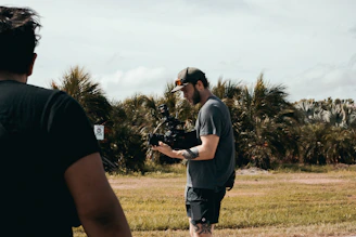 man in grey t-shirt and black shorts standing on green grass field during daytime