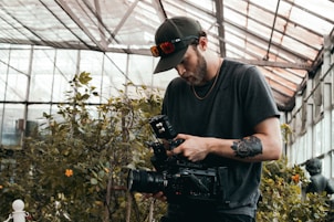 man in black crew neck t-shirt holding black dslr camera