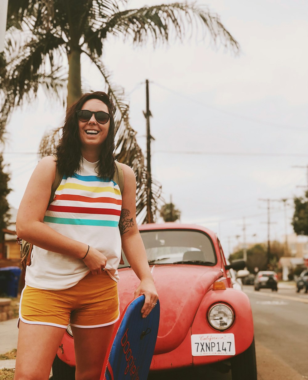woman in white and pink stripe tank top and blue denim shorts standing on road during