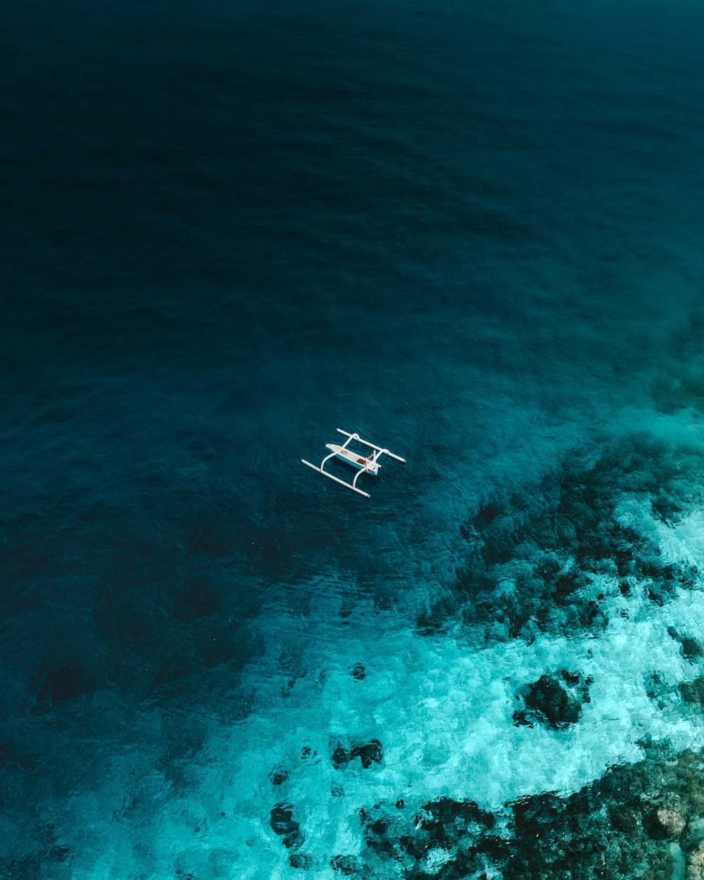 Barco de madera blanca y marrón en agua de mar azul durante el día