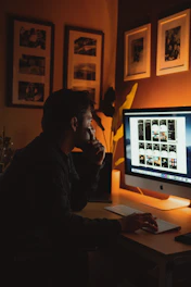 man in black jacket sitting in front of silver imac