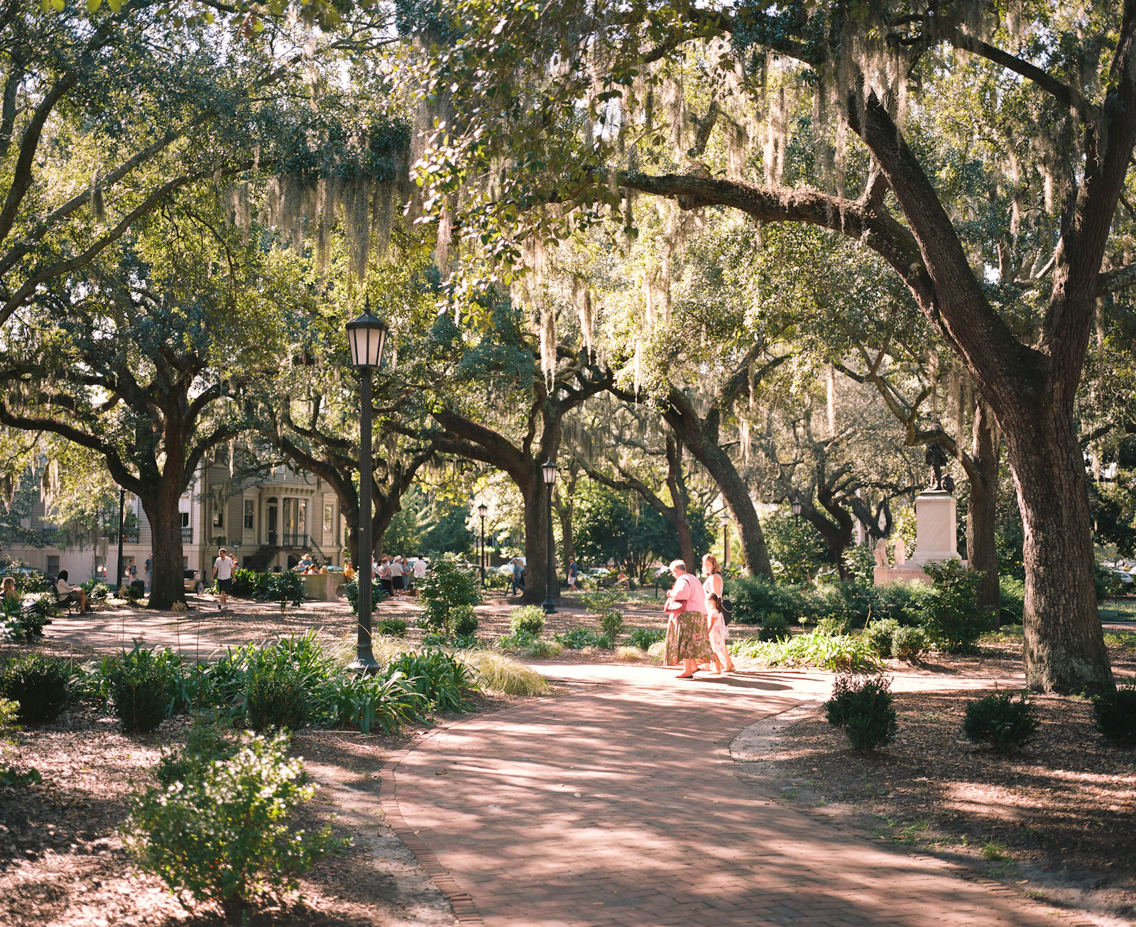 Two friends strolling through a moss-draped Southern square — deciding between Charleston and Savannah for a girls' trip