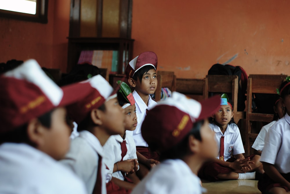 group of children wearing white long sleeve shirt and red cap