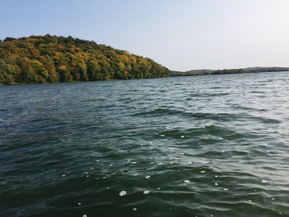 green and brown mountain beside body of water during daytime