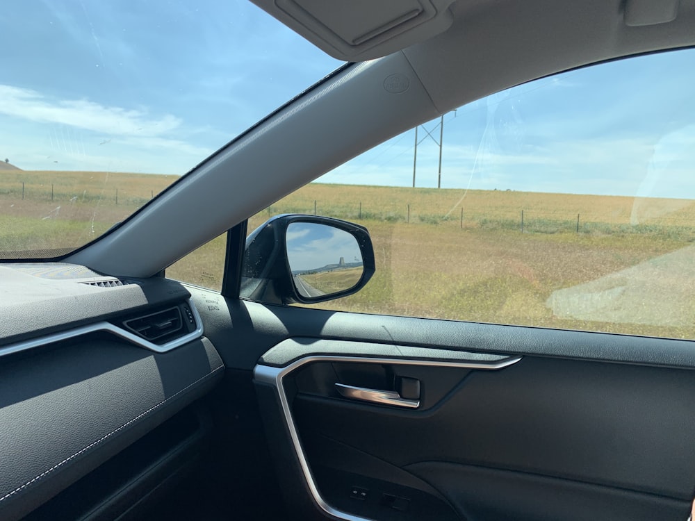 Vue de la fenêtre de la voiture sur le champ d’herbe verte pendant la journée