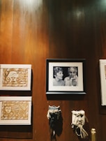 A wall adorned with lively warli art featuring simple white tribal figures on rustic brown paper.