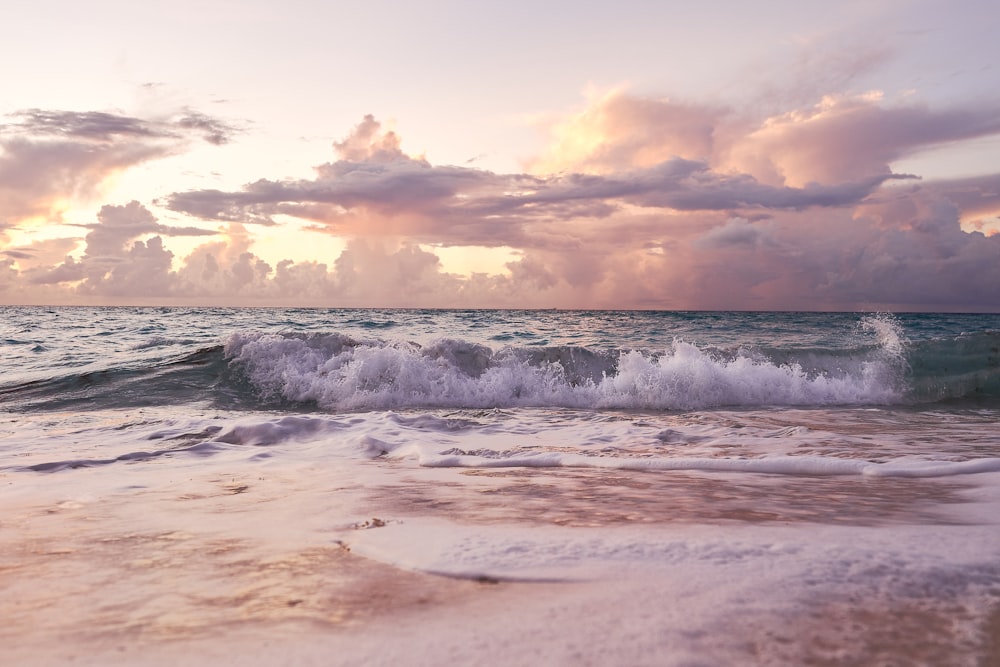 ocean waves crashing on shore during sunset