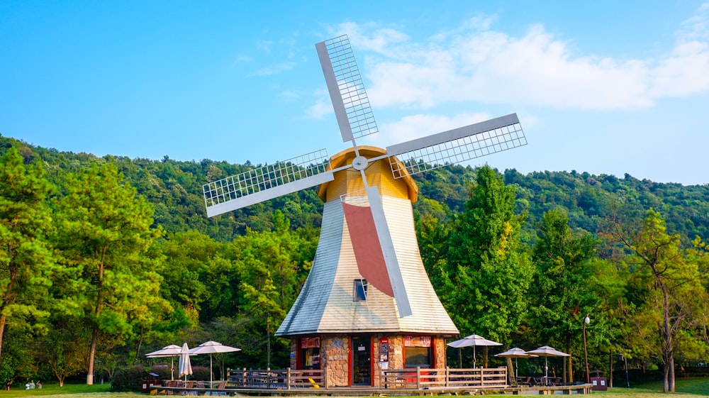 brown and white windmill near green trees during daytime