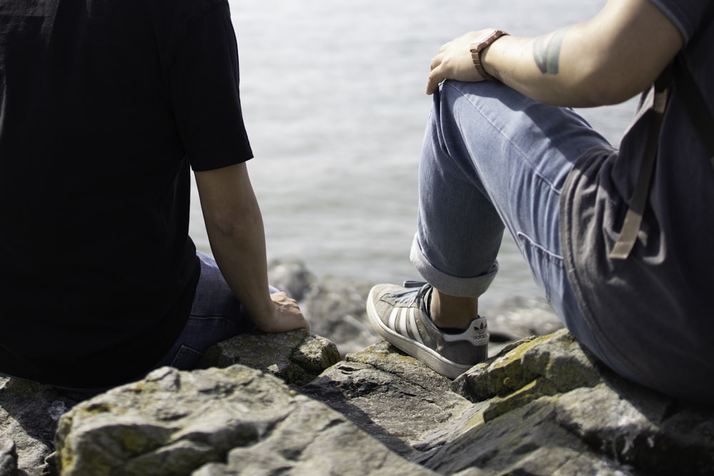 man and woman holding hands while walking on rocky shore during daytime