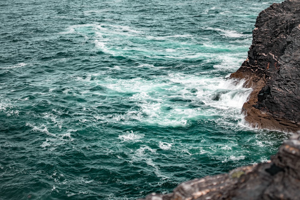 ocean waves crashing on rocks during daytime