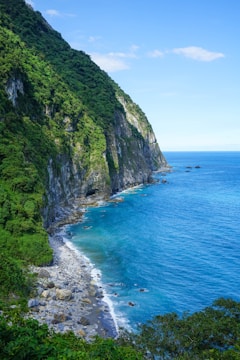 green and gray mountain beside blue sea under blue sky during daytime