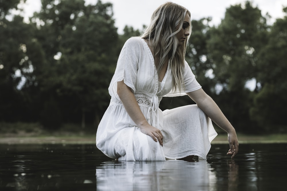 woman in white dress sitting on water during daytime