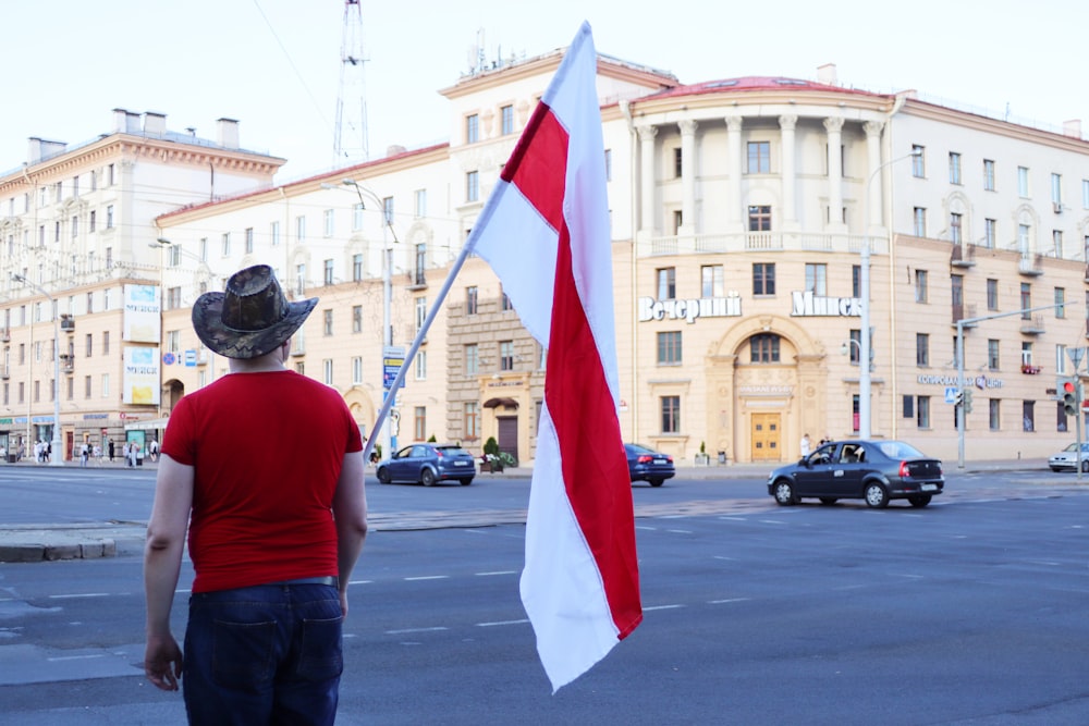 man in red t-shirt holding flag of us a during daytime