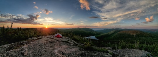 red and white tent on green grass field during sunset in Charlevoix Canada