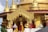 An ornate temple with golden spires and intricate carvings. The architecture features detailed gold embellishments and statues, with red accents. The overall design showcases traditional and religious artistry, with elements of spirituality.