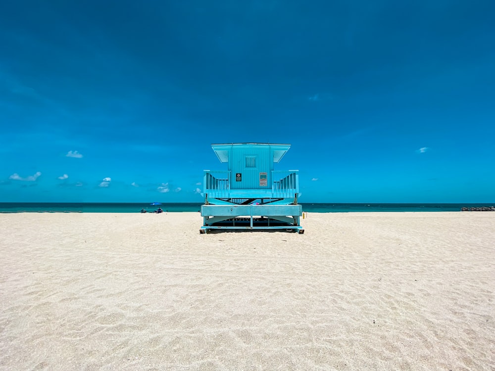 blue and white lifeguard house on beach during daytime