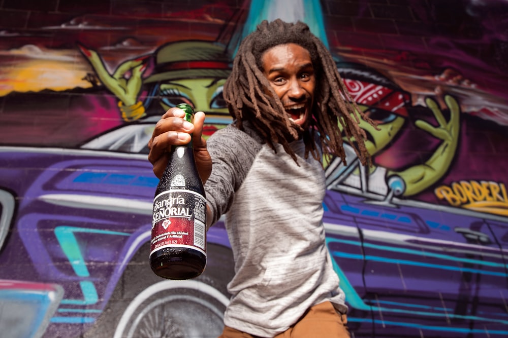 man in gray long sleeve shirt holding black bottle