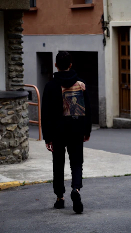 Side view of a person walking down a city street wearing a Calavader hoodie.