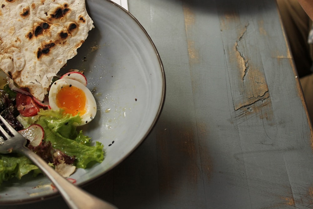 egg with green vegetable on blue ceramic plate